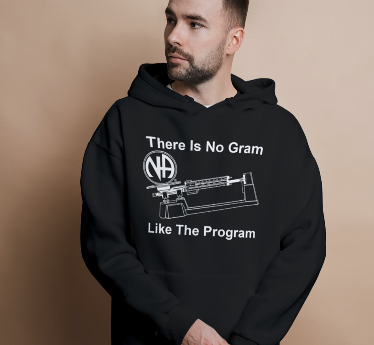 Person wearing a black hoodie with text and logo on a beige background