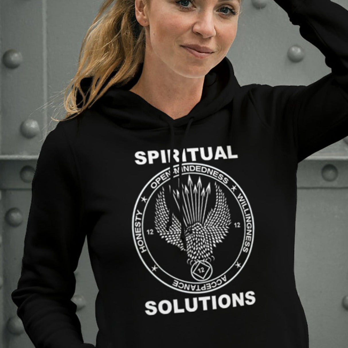 A woman wearing a black hoodie with 'Spiritual Solutions' text and design printed across the front and back.