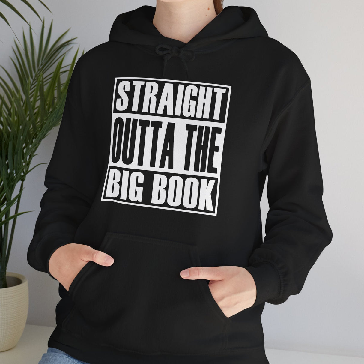 Person wearing a black hoodie with 'Straight Outta The Big Book' text, standing indoors.