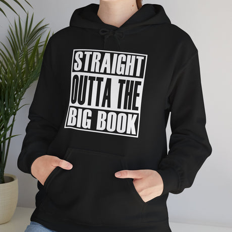Person wearing a black hoodie with 'Straight Outta The Big Book' text, standing indoors.